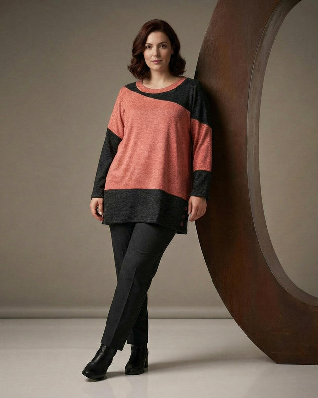 Асиметрична зимна туника в корал и графит голям размер, представена върху модел в цял ръст с елегантни тъмни панталони.