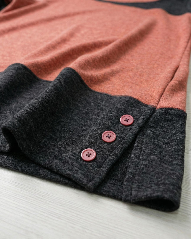 Детайл отблизо на асиметрична зимна туника в корал и графит, показващ трите декоративни копчета на подгъва и меката текстура на материята.