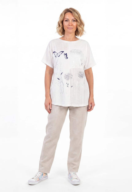 Бяла лятна памучна туника големи размери с флорална апликация и дантела, представена от модел в цял ръст.