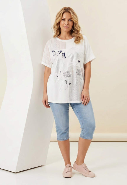 Бяла лятна памучна туника големи размери с флорална апликация и дантела върху манекен, заснета в цял ръст.