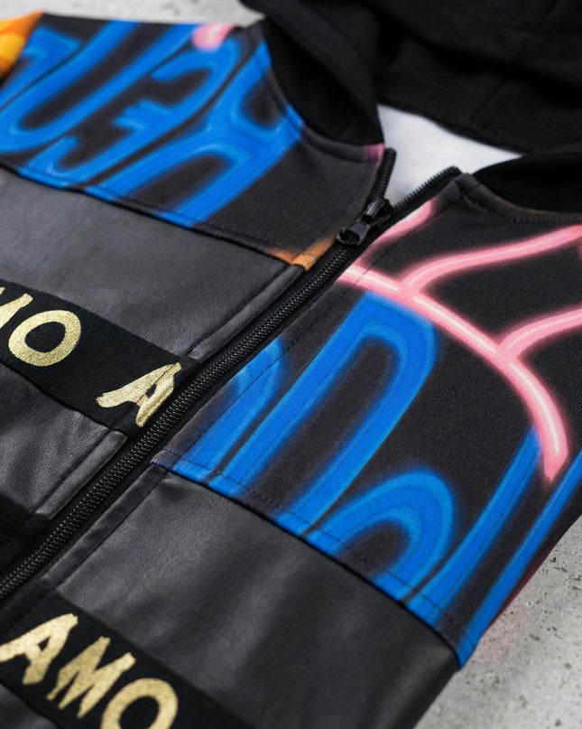 Детайл отблизо на черен макси дамски жакет с качулка. Ясно се виждат закопчаването с цип, панелите от еко кожа и ефектният цветен графити принт.