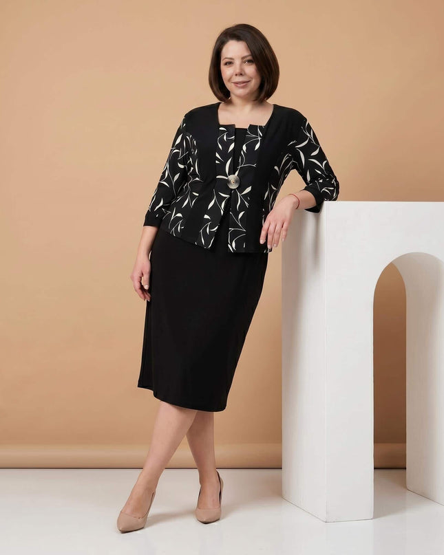 Черна официална рокля големи размери с красива брошка и ефектен бял листен мотив, показана в кадър цял ръст върху модел.