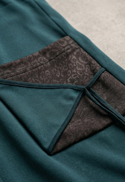 Детайлен кадър на масленозелен макси елек, показващ джоб с ефектен акцент от еко кожа и връзки за регулиране.