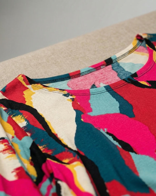 Детайл отблизо на облото деколте на дълга лятна макси туника с абстрактен принт в розово, тюркоаз, жълто и черно.