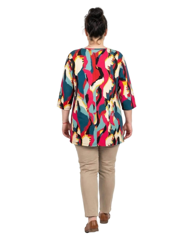 Дълга лятна макси туника с шарен абстрактен принт, представена отзад в цял ръст на бял фон в съчетание с бежов панталон.