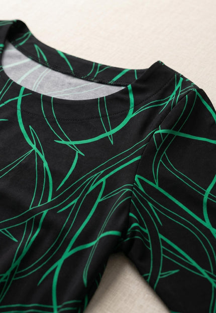 Детайл отблизо на официална макси рокля, показващ класическо обло деколте и модерен абстрактен зелен принт върху черна основа.