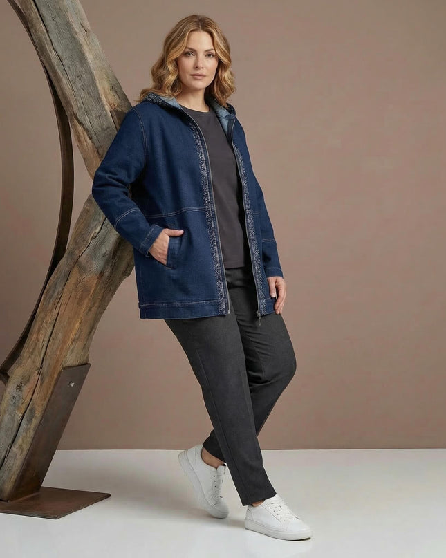 Цял ръст на модел, облечен в дълго тъмносиньо макси дънково яке с качулка и джобове. Ежедневна визия, съчетана с тъмен панталон и бели спортни обувки.