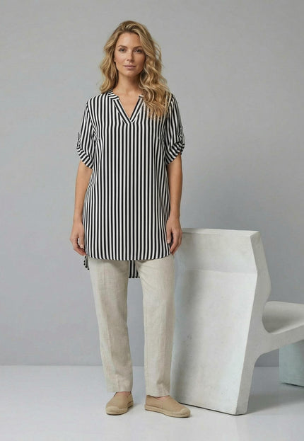 Дамска дълга памучна туника с черно-бяло райе и V-образно деколте. Кадър в цял ръст на модел, комбинирал туниката със светъл панталон.