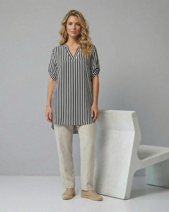 Дамска дълга памучна туника с черно-бяло райе и V-образно деколте. Кадър в цял ръст на модел, комбинирал туниката със светъл панталон.