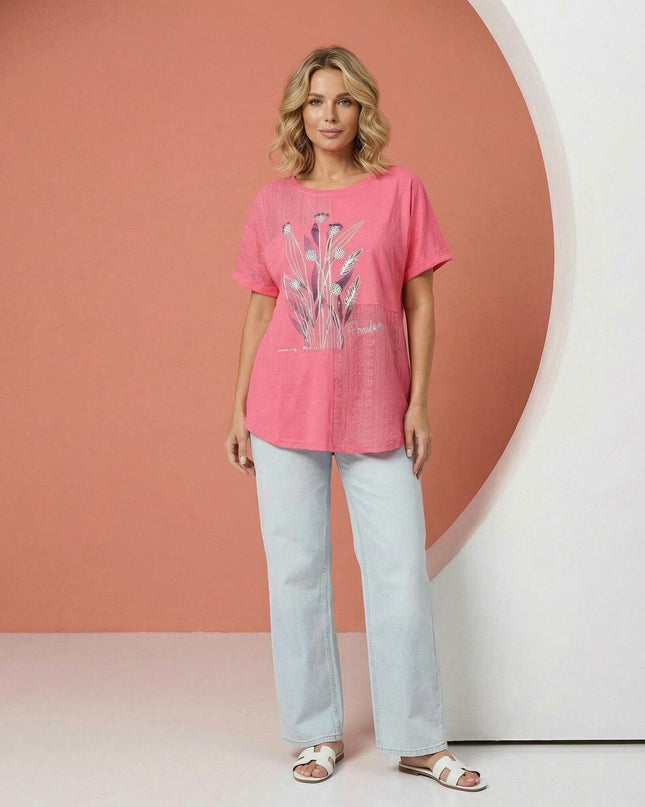 Дамска лятна туника големи размери в коралов цвят с цветя, заснета в цял ръст върху модел, съчетана със светли дънки.