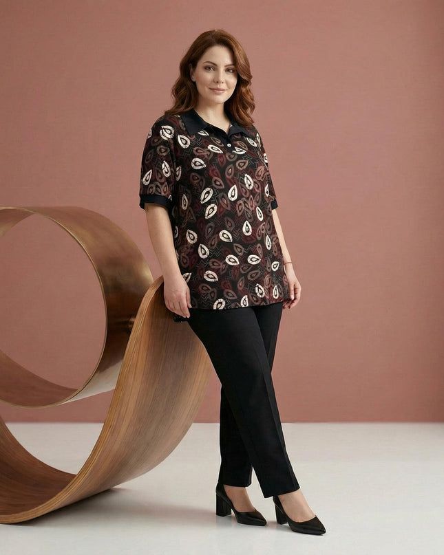 Дамска официална туника големи размери в черен цвят с принт на листа и ефектна яка. Кадър в цял ръст, моделът е съчетал туниката с черен панталон.