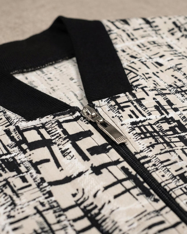 Детайл отблизо на дамски бежов макси жакет, показващ сребристия метален цип, черната рипсена яка и абстрактния геометричен десен.