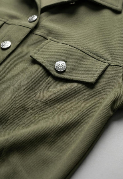 Детайлен кадър на сако в цвят каки от дамски комплект, показващ релефната текстура на материята, джоба с капак и стилните метални копчета.