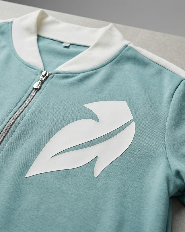 Детайлен кадър на горнище от дамски макси комплект в светлозелено, акцентиращ върху ципа и декоративния елемент от бяла еко кожа.