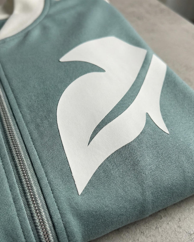 Детайл отблизо на светлозелен дамски макси комплект, показващ декоративен елемент от бяла еко кожа и качествен сребрист цип.