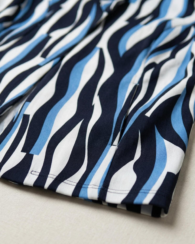 Детайл отблизо на плата на дамско официално сако, акцент върху подгъва и ефектния десен с абстрактни сини и черни мотиви на бял фон.