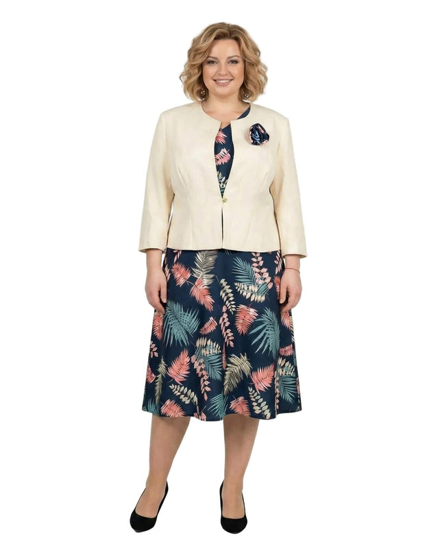 Елегантен дамски костюм големи размери, съчетаващ тъмносиня рокля с цветни мотиви и бежово сако, заснет в цял ръст.