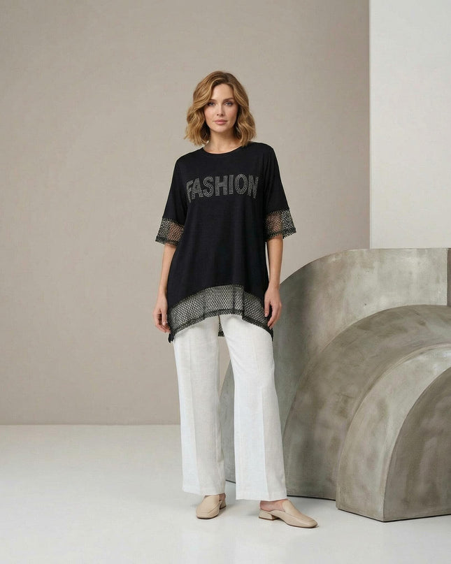Снимка в цял ръст на елегантна черна асиметрична туника големи размери с мрежа по ръкавите и подгъва, съчетана с бели панталони.