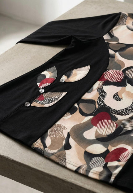 Детайлен кадър на елегантна черна туника с абстрактен цветен принт, акцентиращ върху декоративните апликации във форма на листа с копчета.