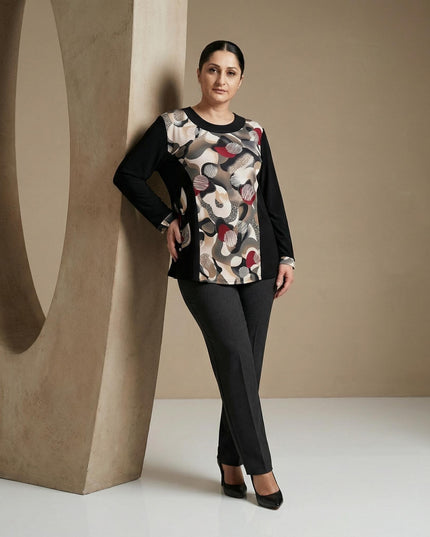 Елегантна черна туника с централен абстрактен принт в бежово и червено, заснета в цял ръст върху модел до декоративна колона.