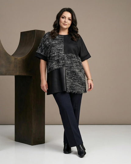 Елегантна черна туника в цял ръст, съчетаваща релефна текстура и панел от еко кожа, демонстрираща свободната разкроена кройка.