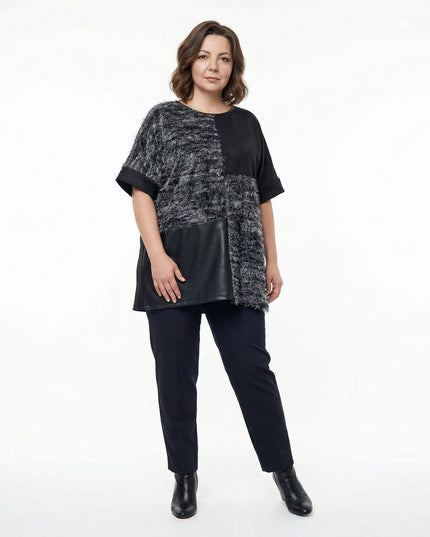 Елегантна черна туника с релефна мъхеста текстура и панел от еко кожа, представена в цял ръст. Модел с асиметричен дизайн и свободна кройка за макси дами.