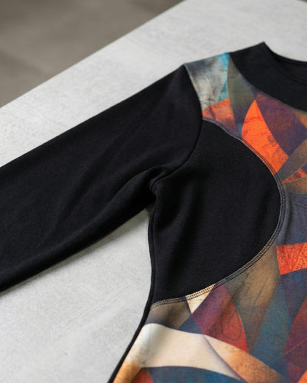 Детайлен кадър на елегантна есенна туника с витражен принт, показващ черния дълъг ръкав, облото деколте и връзката с цветния преден панел.