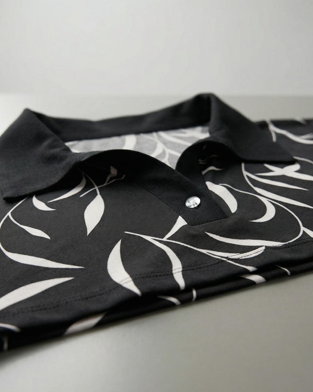 Детайлен кадър на елегантна макси туника с абстрактен принт, фокусиращ се върху черната яка и V-образното деколте с копче.