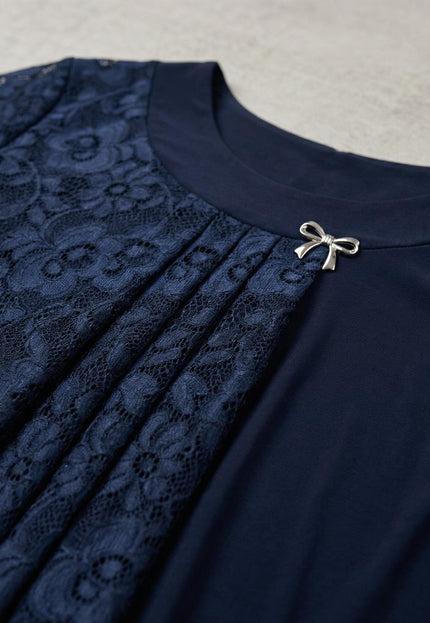 Детайлен кадър на елегантна макси туника в тъмносиньо, показващ дантеления панел с плисета и декоративна сребриста брошка на деколтето.