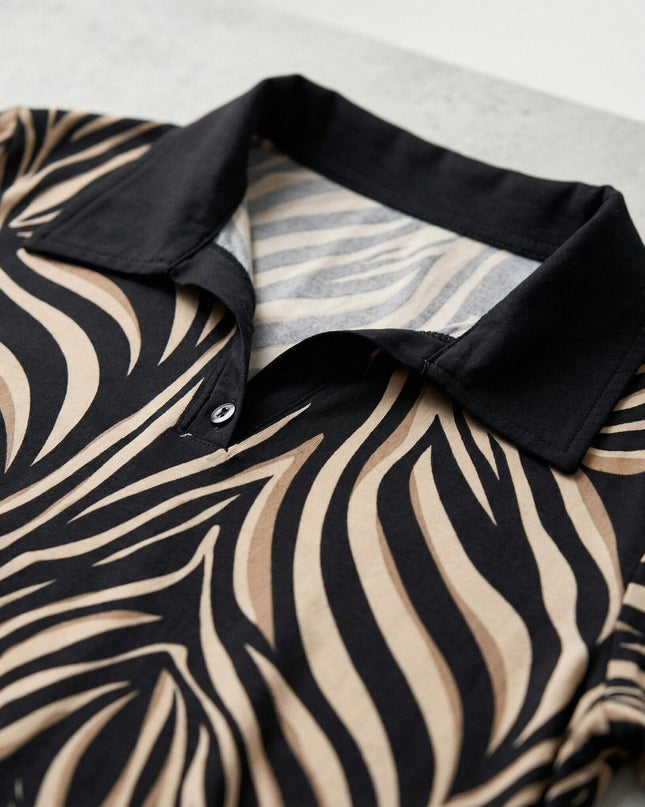 Детайл отблизо на черната яка и V-образното деколте на елегантна макси туника с абстрактен зебра принт в черно и бежово.
