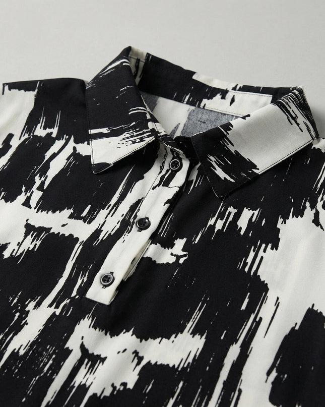 Детайл отблизо на елегантна макси риза в черно и бяло с абстрактен принт, показващ класическа якичка и малки копчета.