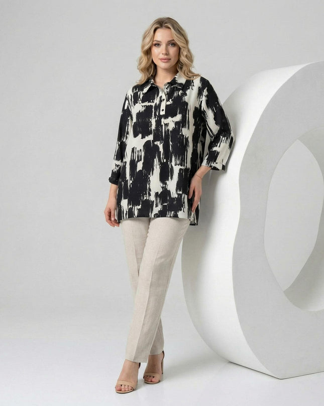 Елегантна официална макси риза в черно и бяло с абстрактен принт и 7/8 ръкави, представена от модел в цял ръст, комбинирана със светъл панталон.