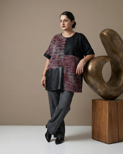 Елегантна официална макси туника с кожени елементи и текстуриран пух, заснета в цял ръст върху модел до декоративна скулптура.