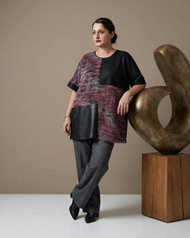 Елегантна официална макси туника с кожени елементи и текстуриран пух, заснета в цял ръст върху модел до декоративна скулптура.