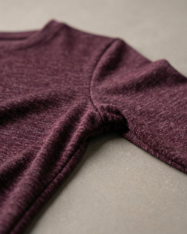 Детайл отблизо на шева на ръкава и текстурата на елегантна дамска рокля в цвят бордо меланж, изработена от мека и еластична вискозна материя.