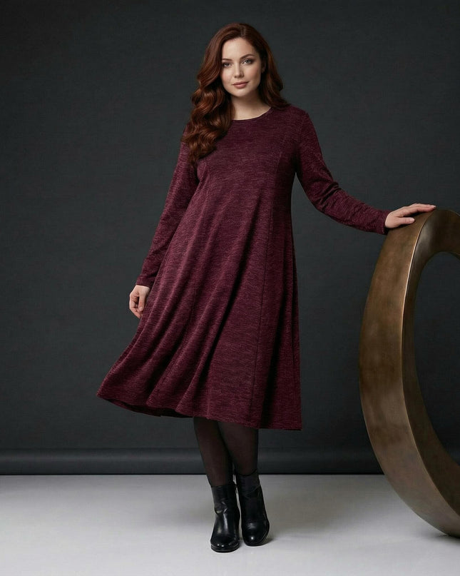 Елегантна разкроена рокля в цвят бордо меланж за макси дами, представена в цял ръст. Зимен модел с дълъг ръкав, обло деколте и свободна кройка.