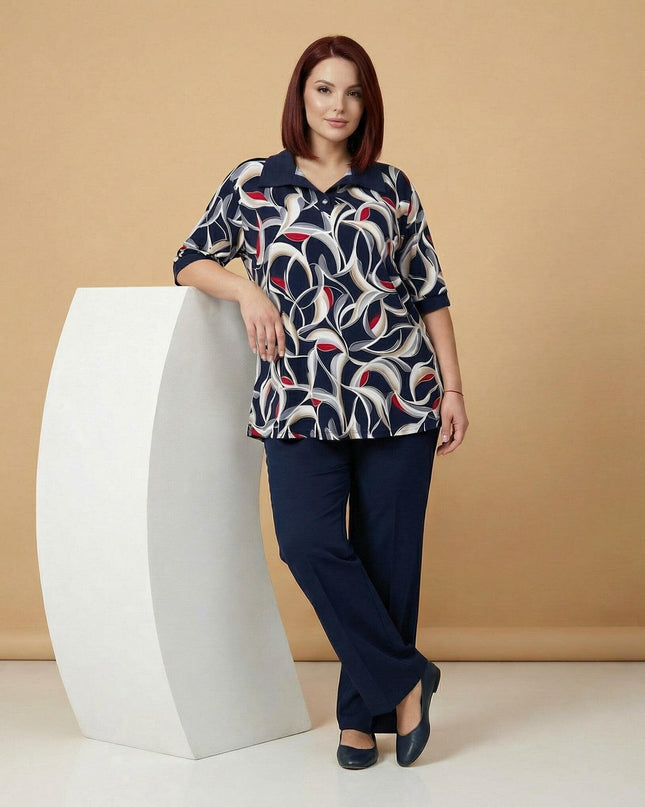 Елегантна разкроена туника големи размери в шарен абстрактен десен, показана в цял ръст, съчетана с изчистен тъмносин панталон.
