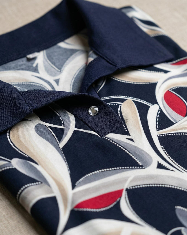 Детайл отблизо на елегантна туника, показващ тъмносиня яка тип поло с декоративно копче и абстрактен шарен десен в синьо, бяло и червено.