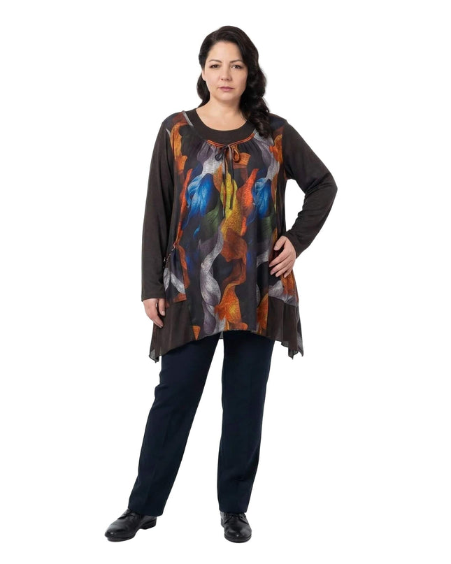Елегантна разкроена туника в големи размери с цветен абстрактен принт и асиметричен подгъв, представена в цял ръст.