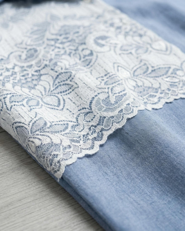 Детайл отблизо на красивата бяла дантела с флорални мотиви върху синята ленена материя на тази елегантна макси риза.