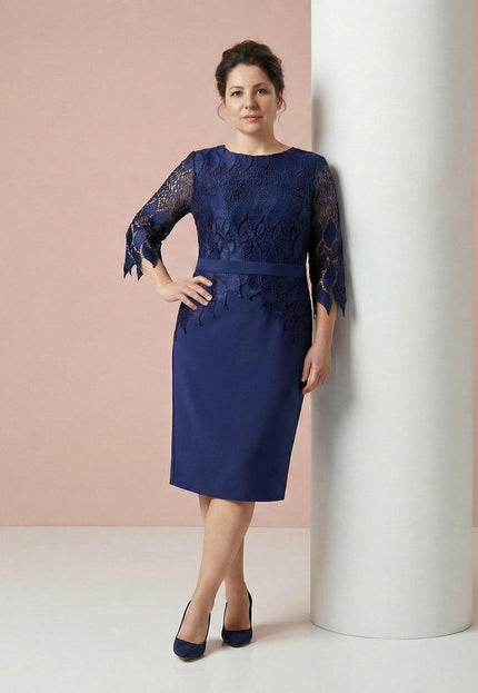 Елегантна тъмносиня макси рокля с дантелена горна част и колан, представена в цял ръст до бяла колона