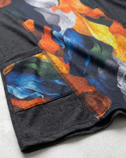 Детайлна снимка на текстила на елегантна туника с абстрактен принт, изобразяващ есенни листа в синьо и оранжево, с видим шев и част от джоба.