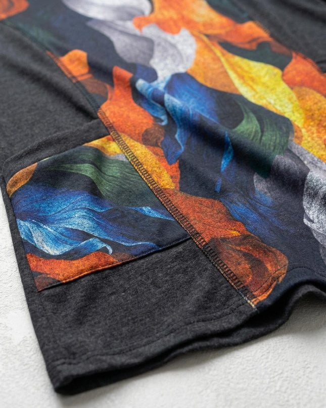 Детайлна снимка на текстила на елегантна туника с абстрактен принт, изобразяващ есенни листа в синьо и оранжево, с видим шев и част от джоба.