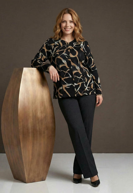 Елегантно черно макси сако с абстрактен десен в бежово, представено върху модел в цял ръст, позиращ до голяма декоративна ваза.