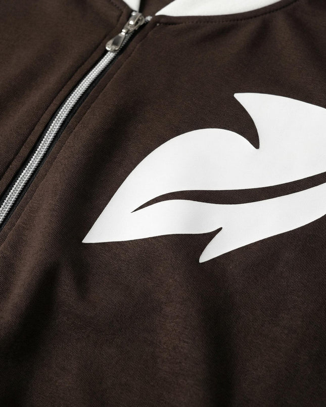 Детайл отблизо на горнището от кафяв дамски макси комплект, акцентиращ върху белия графичен принт и металния цип на дрехата.