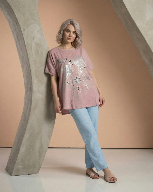Дамска лятна памучна туника в нежно розово със сребристи щампи на цветя и пеперуди, снимана в цял ръст върху модел.