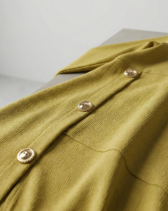 Детайл отблизо на макси официална рокля в цвят горчица, показващ нежната рипсена текстура на материята и три златни декоративни копчета.