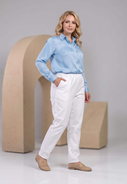 Официален дамски бял панталон големи размери с удобна права кройка. Кадър в цял ръст на модел в студио със светлосиня риза.