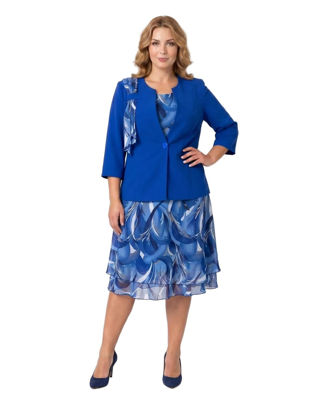 Официален дамски костюм в кралскосин цвят със сако и шифонена разкроена рокля с принт, сниман в цял ръст на бял фон.