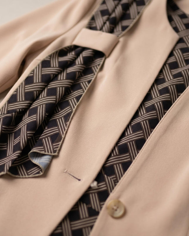 Детайл отблизо на елегантно бежово сако от официален дамски костюм, акцентиращ върху красивия геометричен мотив и закопчаването с копче.